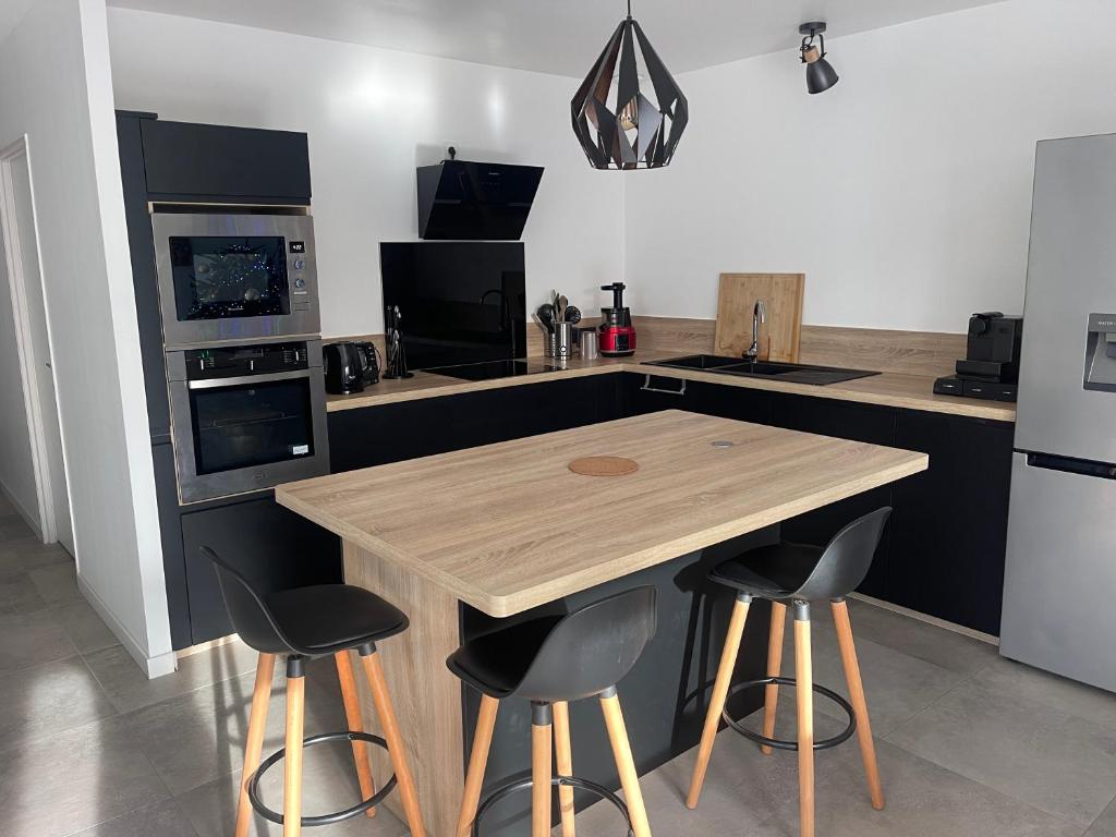 - une cuisine avec une table en bois et deux tabourets de bar dans l'établissement Maison au cœur du médoc, à Cussac-Fort-Medoc