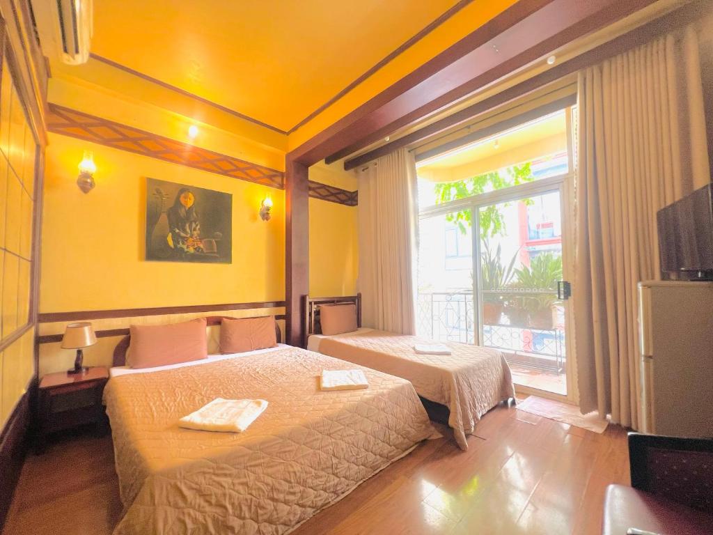 a hotel room with two beds and a window at Bi Saigon Hotel in Ho Chi Minh City