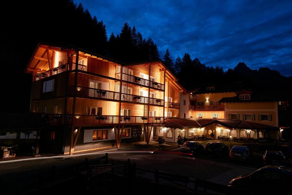 a building with cars parked in a parking lot at night at Hotel Valacia in Pozza di Fassa