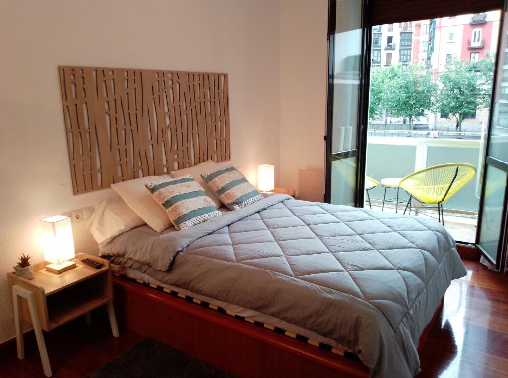 una camera da letto con un letto grande con una grande finestra di Centro de Bilbao, amplio, ascensor a Bilbao