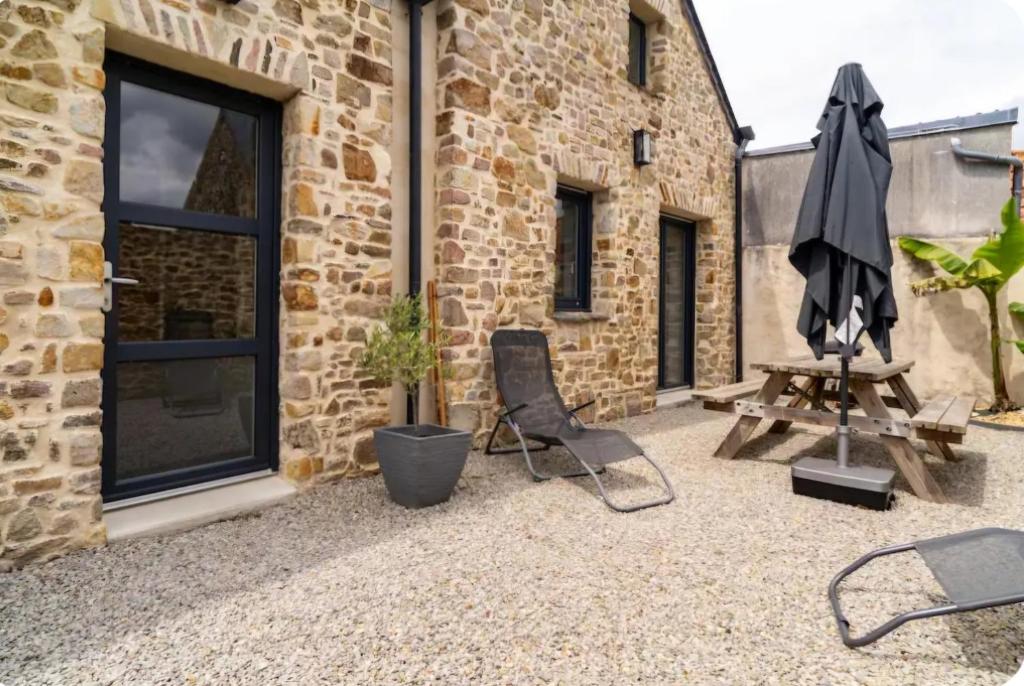 - une terrasse avec 2 chaises, un parasol et une table dans l'établissement Maison de charme, à Créances