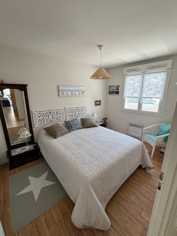 une chambre avec un grand lit et un miroir dans l'établissement Appartement centre ville avec parking, à Quiberon