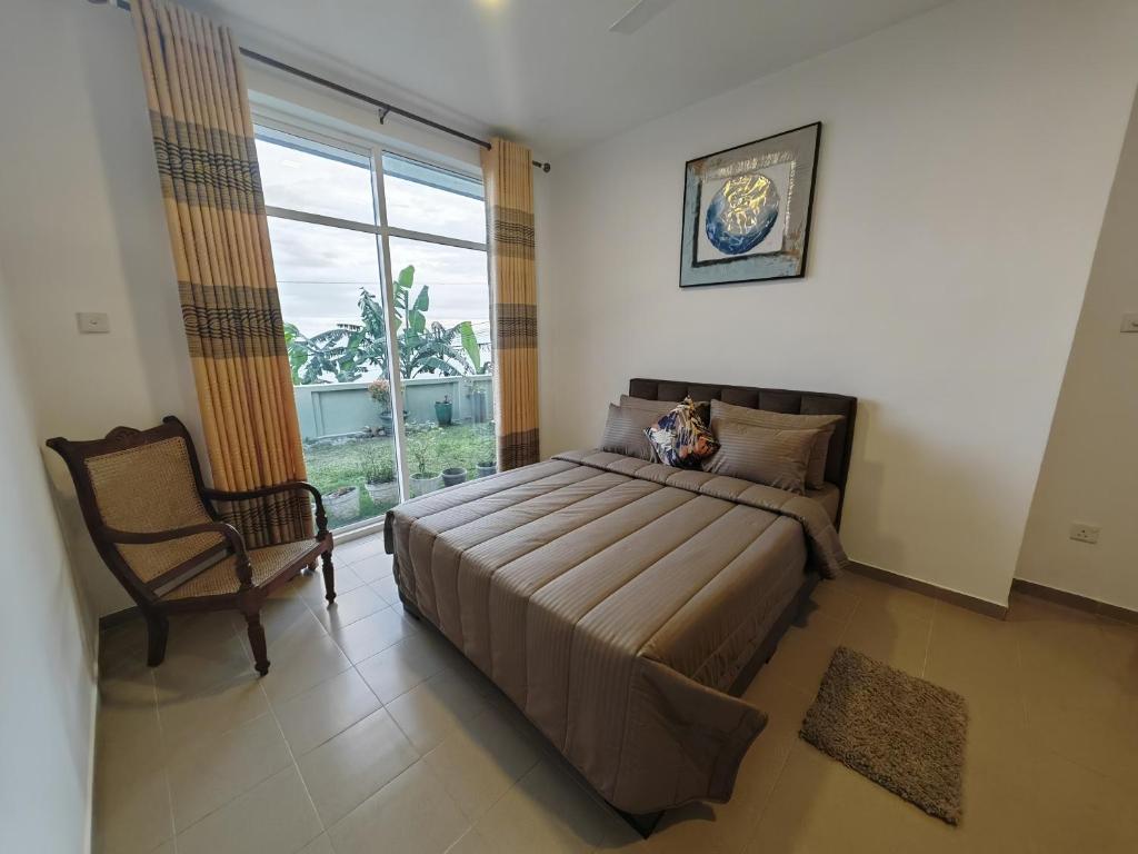 a bedroom with a bed and a chair and a window at Trail Town Lodge in Haputale