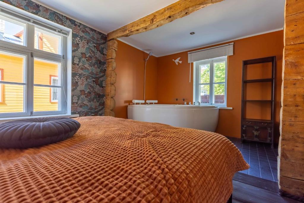 an orange bedroom with a bed and a bath tub at Mönus Pesa in Kuressaare