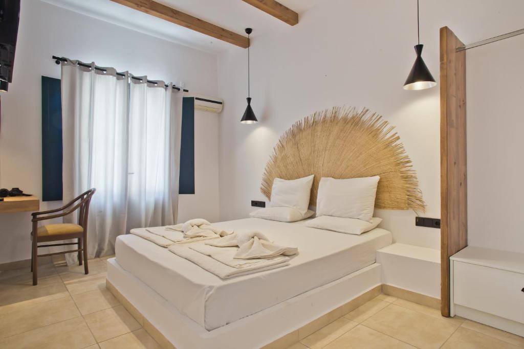 a bedroom with a white bed with a wooden headboard at Kyra Panagia Hotel in Kyra Panagia
