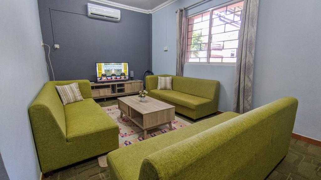 a living room with two green chairs and a tv at Bunut Centre Stay in Bandar Seri Begawan
