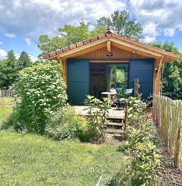 une petite maison bleue avec une personne assise à une table dans l'établissement Bienvenue moto vélo lanquais varennes, à Varennes