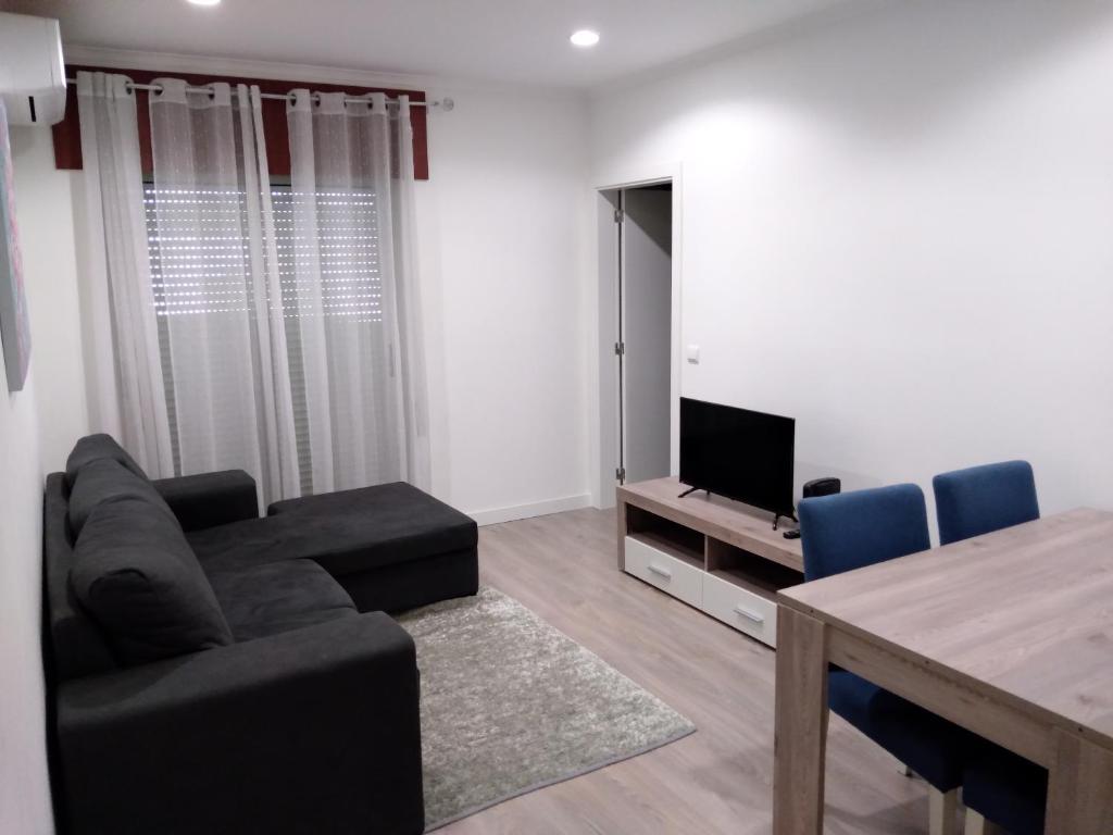 a living room with a couch and a table and a television at Alojamento Almirante in Viseu