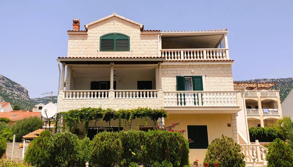 a large white house with a balcony at Apartmani Marijana in Bol