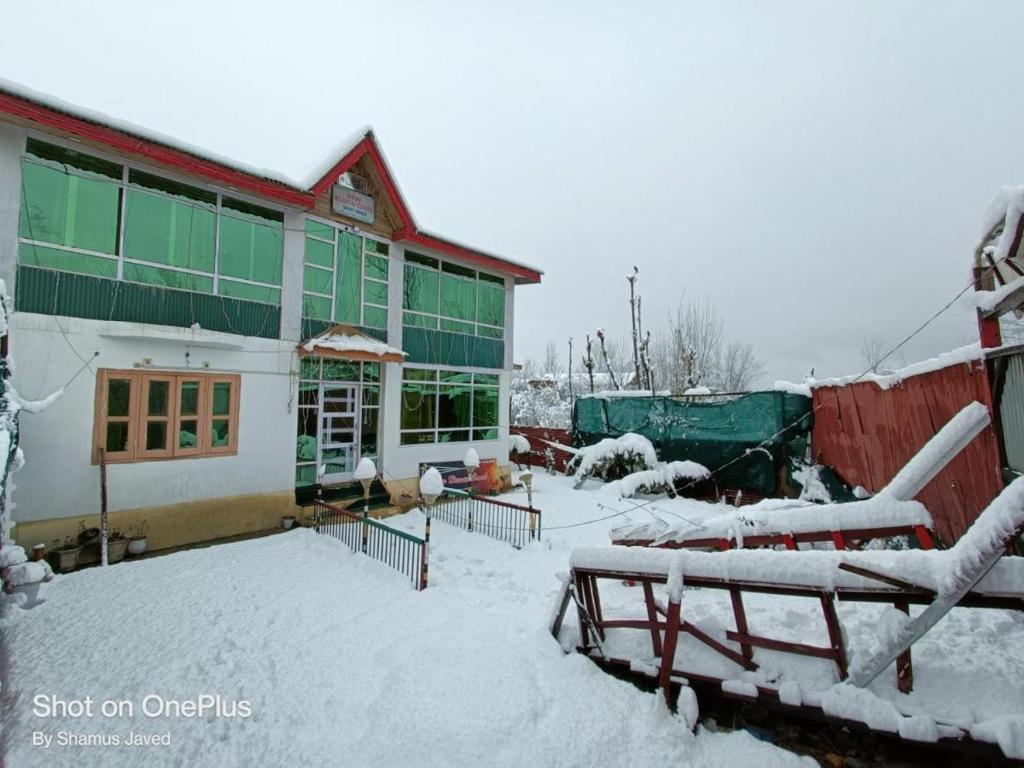 a building with snow on the ground in front of it at Shamus Javed Homestay in Srinagar