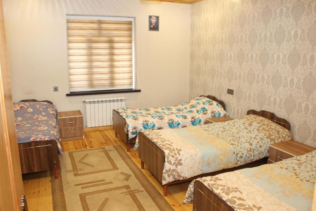 una habitación con tres camas y una ventana en Familihome, en Ganja