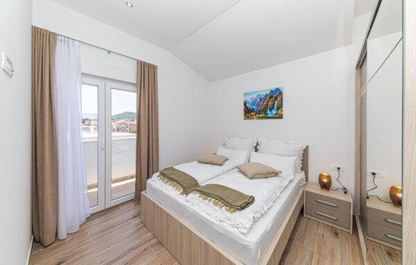 a white bedroom with a large bed and a window at Apartmani Kornelija in Kaštela