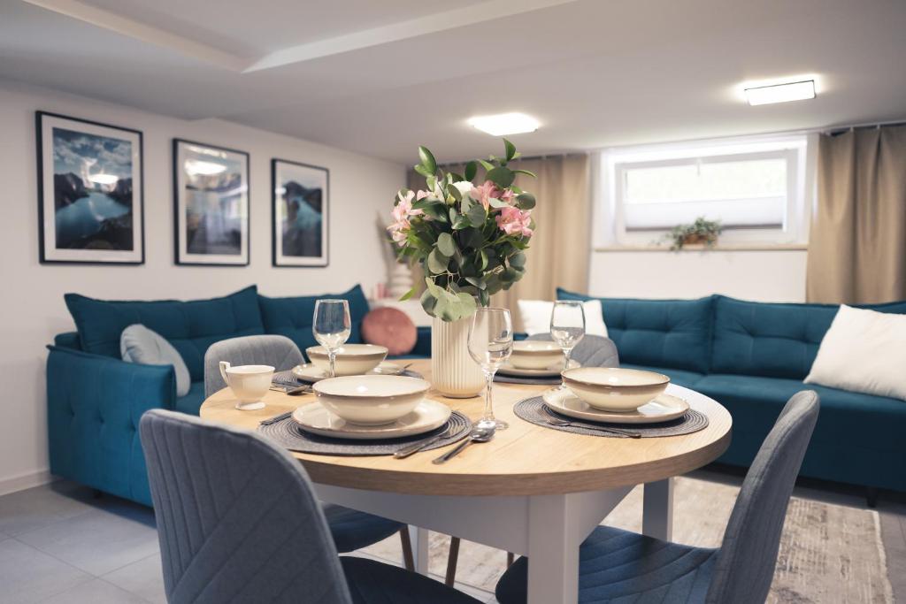 a dining room with a table and a blue couch at Zielony Apartament in Bachowice