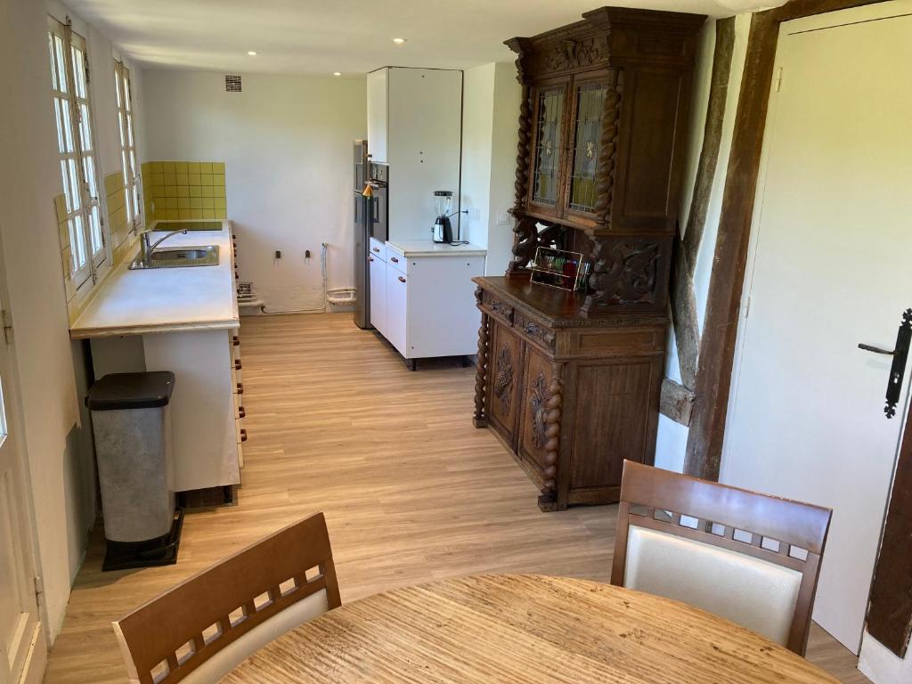 une cuisine avec une table et un réfrigérateur dans l'établissement Maison en colombage - Les Iris, à Le Pré-dʼAuge