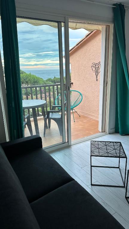 een woonkamer met een bank en een balkon met een tafel bij Lumineux studio vue mer in Sainte-Maxime