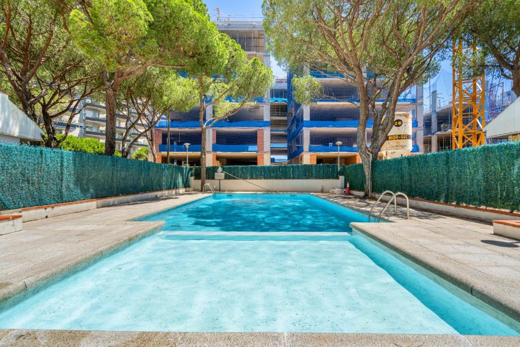 ein Pool mit Bäumen und ein Gebäude im Hintergrund in der Unterkunft WELCS APARTAMENTO 165 PDA con piscina in Platja  d'Aro