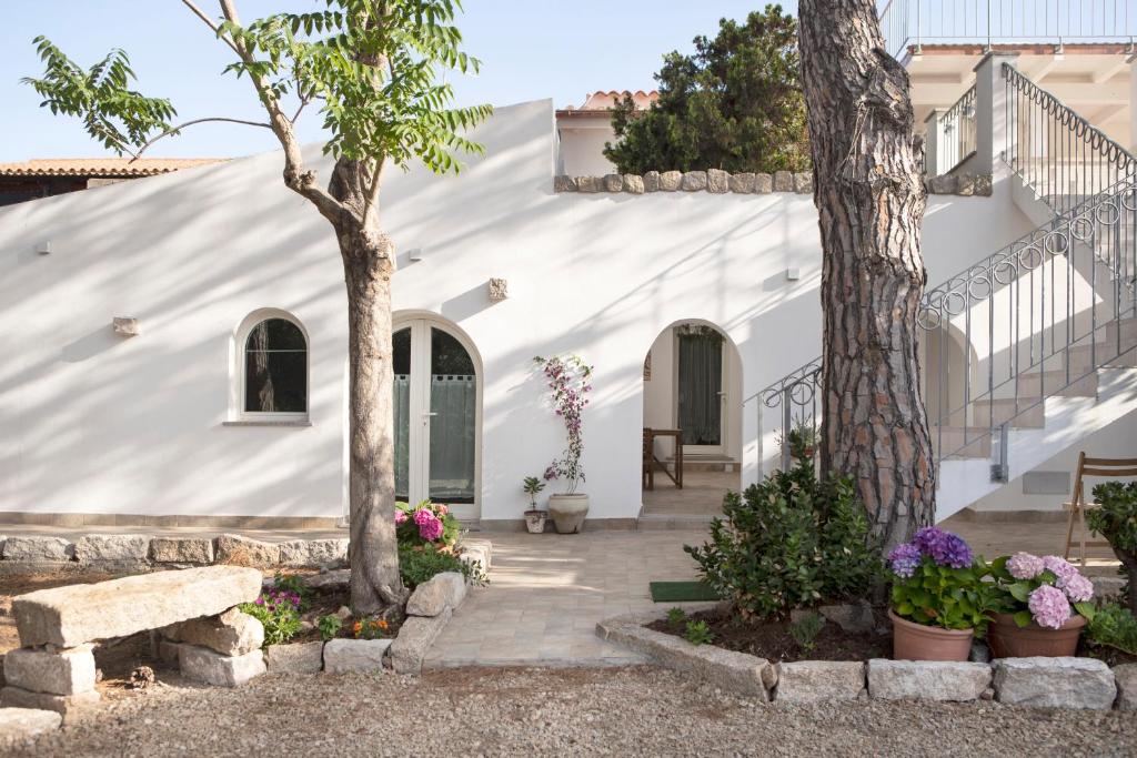 a white house with trees and flowers at Villa Silvia Apartments in La Maddalena