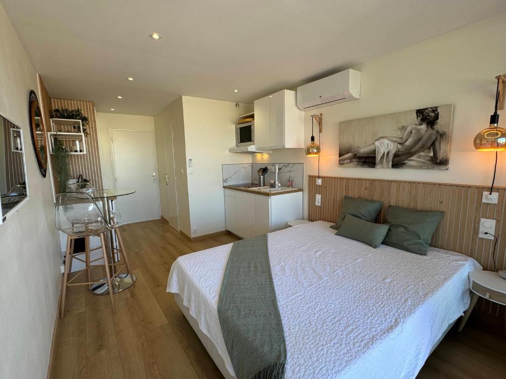une chambre avec un grand lit et une cuisine dans l'établissement Village Naturiste Héliopolis FGH, au Cap d'Agde