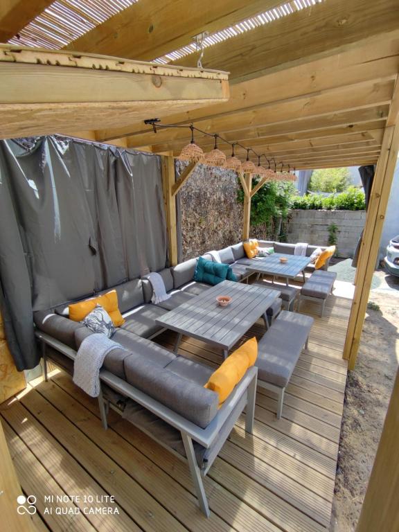 a patio with a couch and tables on a deck at MER 12 à 14 pers L'Aiguillon sur mer in LʼAiguillon-sur-Mer