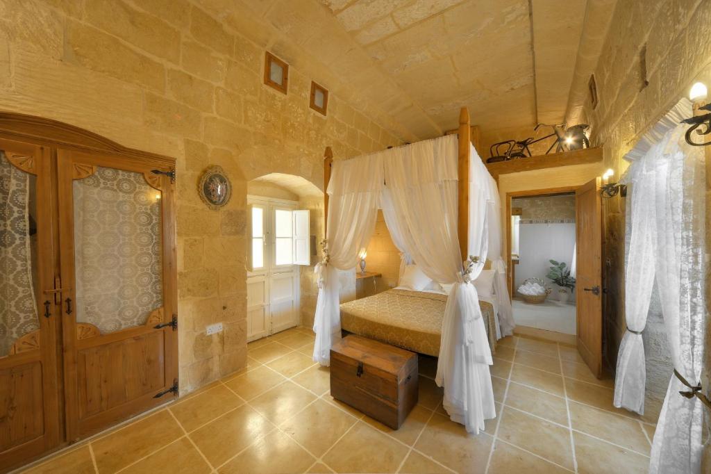 a bedroom with a bed with a canopy at Gozo Break Farmhouses in Kerċem