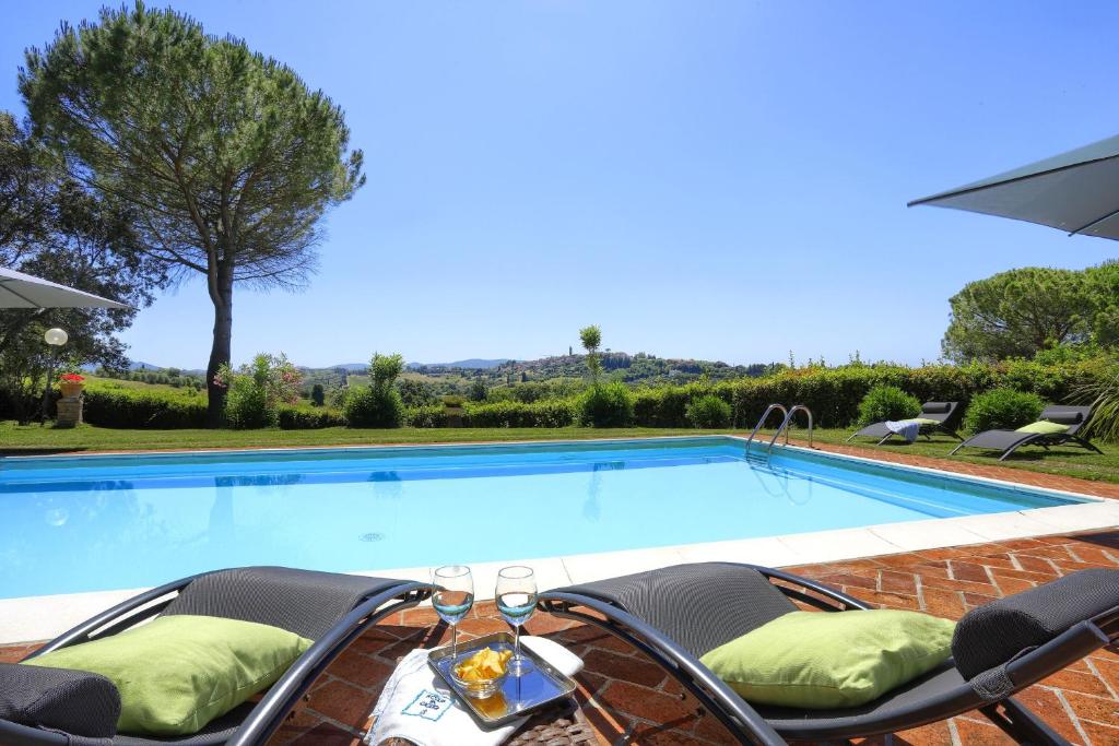 - une piscine avec deux chaises en face dans l'établissement Villa Orsini Peccioli - Villa storica ad uso esclusivo con piscina, à Peccioli