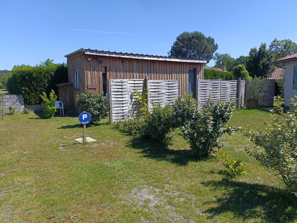 a garden with a building and a sign in the grass at Gîte Lauraët in Linxe