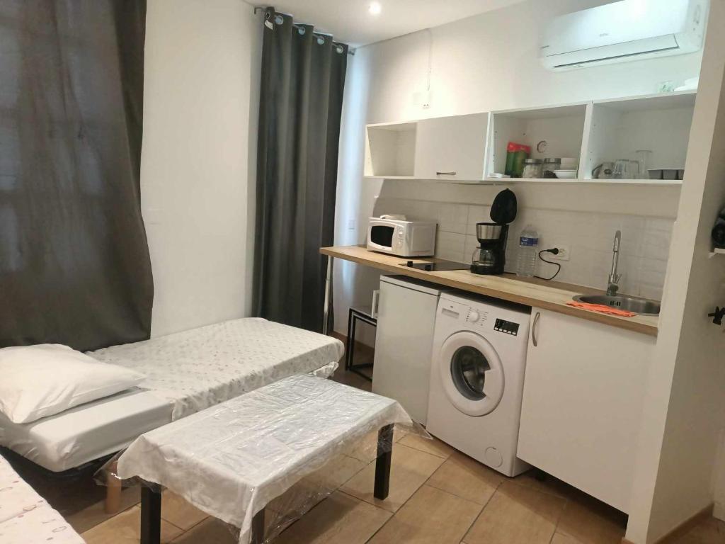 une petite pièce avec une machine à laver et une cuisine dans l'établissement Mer, à Avignon