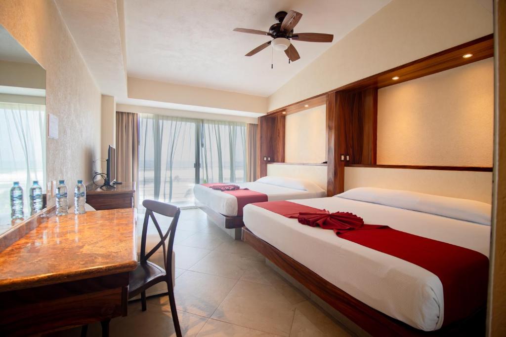 a hotel room with two beds and a table at Mishol Bodas Hotel & Beach Club Acapulco Diamante in Acapulco