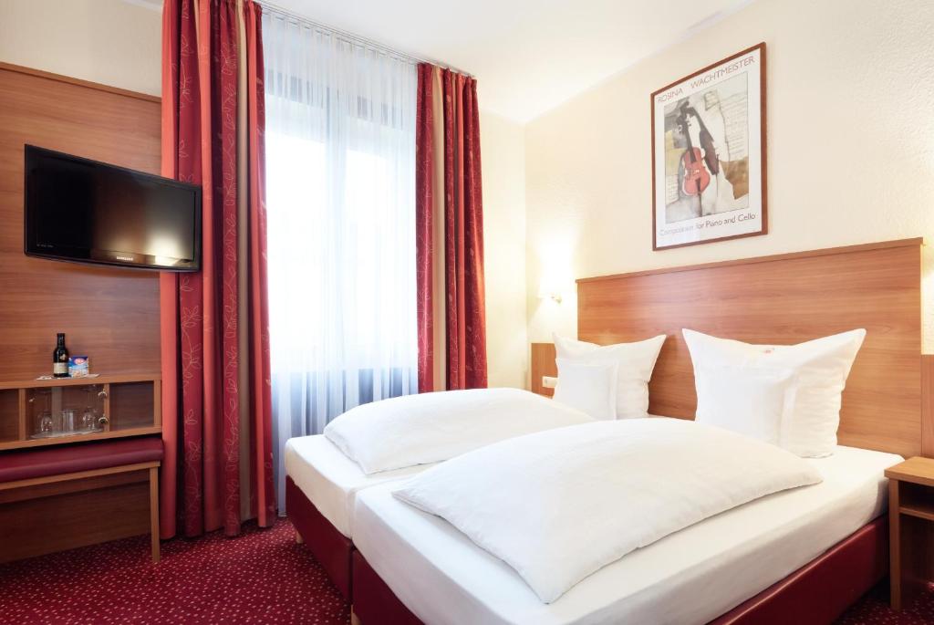 ein Hotelzimmer mit 2 Betten und einem TV in der Unterkunft Doria in Düsseldorf