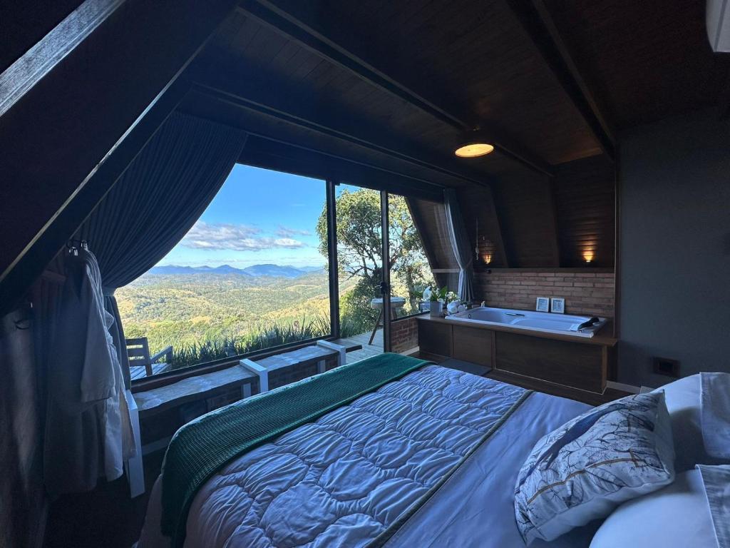 a bedroom with a large window with a bed and a tub at Casa da Mata in São Bento do Sul