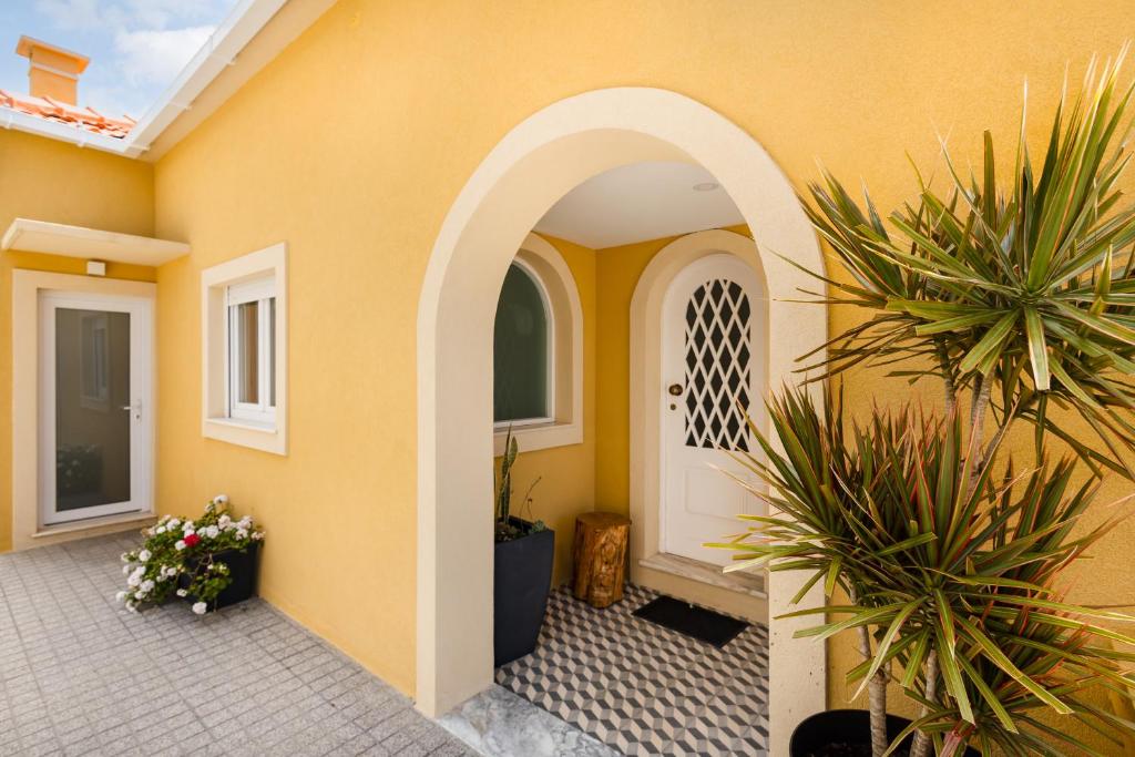 an arched entryway to a yellow house with plants at Pontes Guest House in Arcozelo