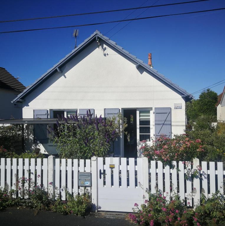 une maison blanche avec une clôture blanche dans l'établissement Maison de pêcheur à 150 m de la mer avec jacuzzi, à Ouistreham