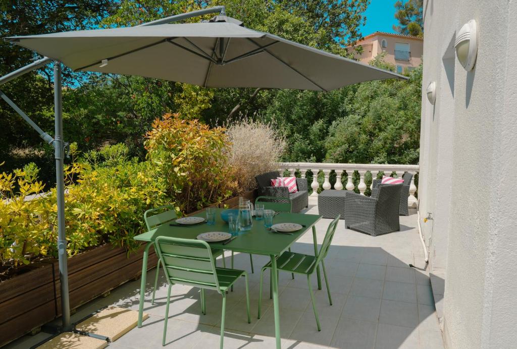une table verte et des chaises sous un parasol dans l'établissement La Bastide du Cap Brun, à Toulon