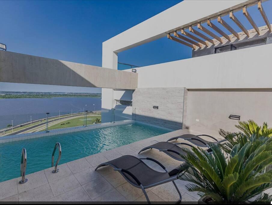 a swimming pool with chairs next to a building at Vista al Río Paraguay, Costanera Asu in Asuncion