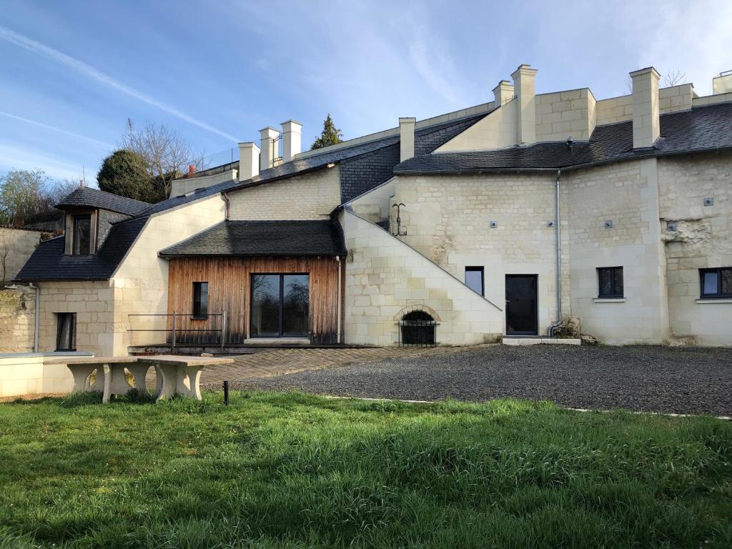 - un grand bâtiment en pierre avec un banc devant dans l'établissement Troglo Saumurois, à Chacé