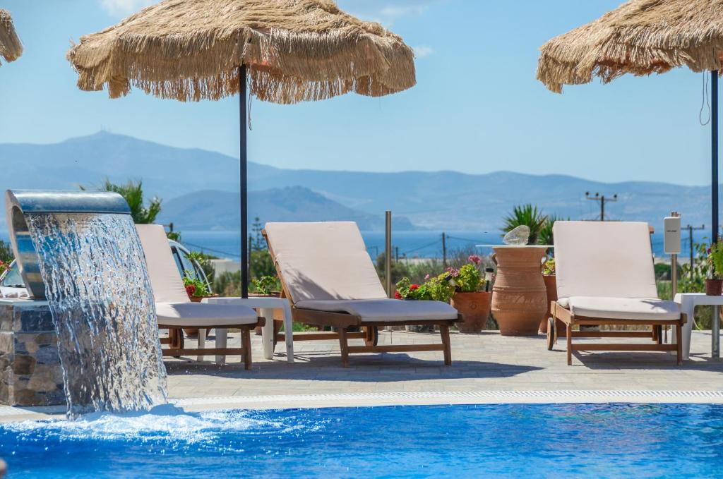 een groep stoelen en parasols naast een zwembad bij Orama Studios in Agia Anna Naxos