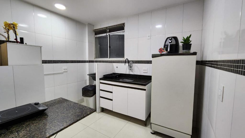 a white kitchen with a sink and a stove at AP 3 quartos -2min da ARENA MRV e Expominas- BH in Belo Horizonte
