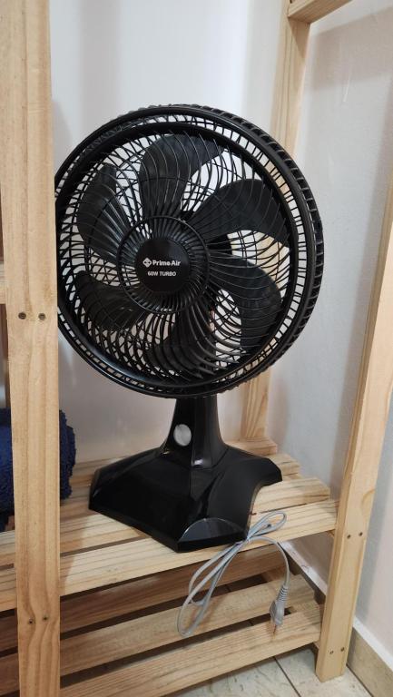 a black fan sitting on top of a wooden shelf at AP 3 quartos -2min da ARENA MRV e Expominas- BH in Belo Horizonte