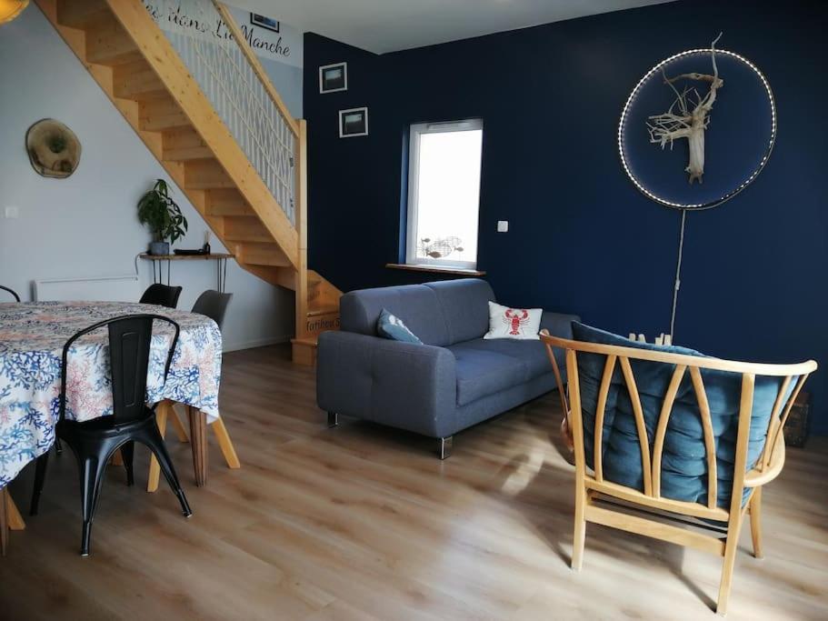 un salon avec un canapé bleu et une table dans l'établissement Les Ganivelles, maison à 350 m de la plage, à Bretteville-sur-Ay