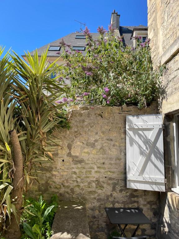 un mur de briques avec une fenêtre avec des fleurs dessus dans l'établissement Le Nid d Abbaye, à Caen
