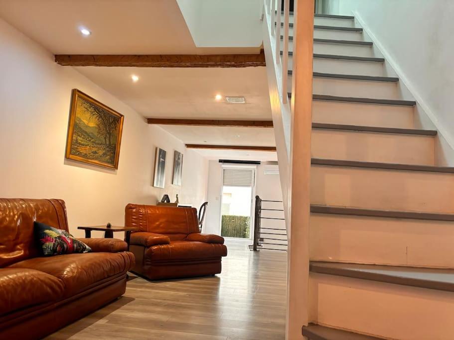 Il comprend un salon doté d'un mobilier en cuir brun et d'un escalier. dans l'établissement Maison 8 min plage 6 personnes, à Bompas