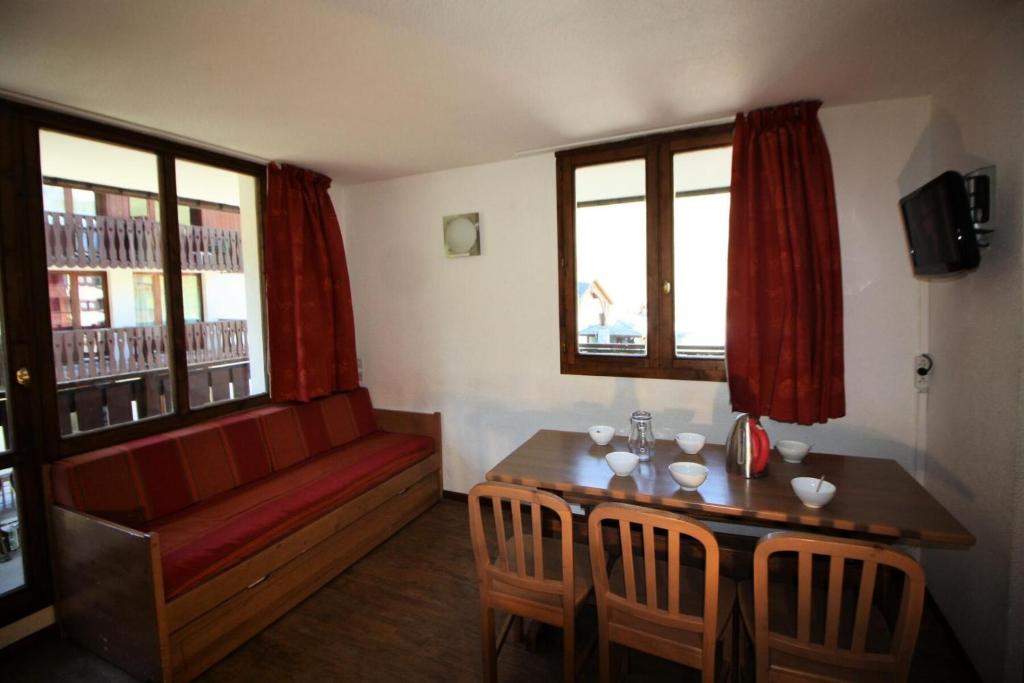 un salon avec une table et un canapé rouge dans l'établissement Résidence Rond Point Des Pistes - proximité immédiate des pistes et des remontées mécaniques (Funiculaire) MAE-3472, à Tignes