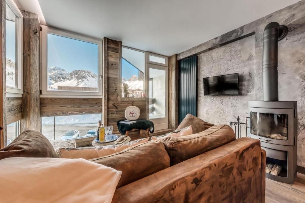 a living room with a large couch and a fireplace at Résidence Roches Rouges A - Pied de pistes, appartement chaleureux et douillet MAE-3523 in Tignes