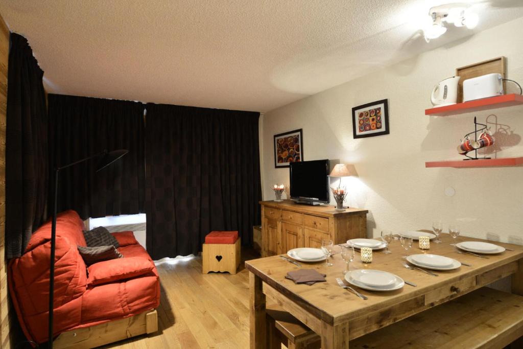 un salon avec une table et un canapé rouge dans l'établissement Résidence Andromede - 3 Pièces pour 6 Personnes 71, à Mâcot La Plagne