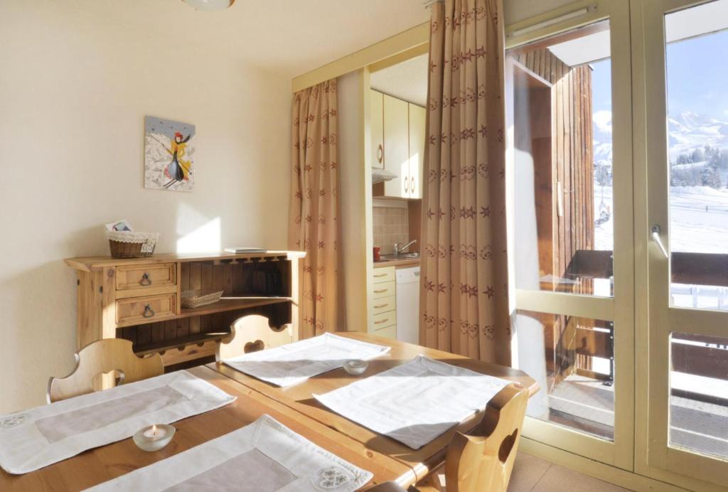 une salle à manger avec une table en bois et une fenêtre dans l'établissement Residence 3000 - Studio pour 4 Personnes 13, à Mâcot La Plagne