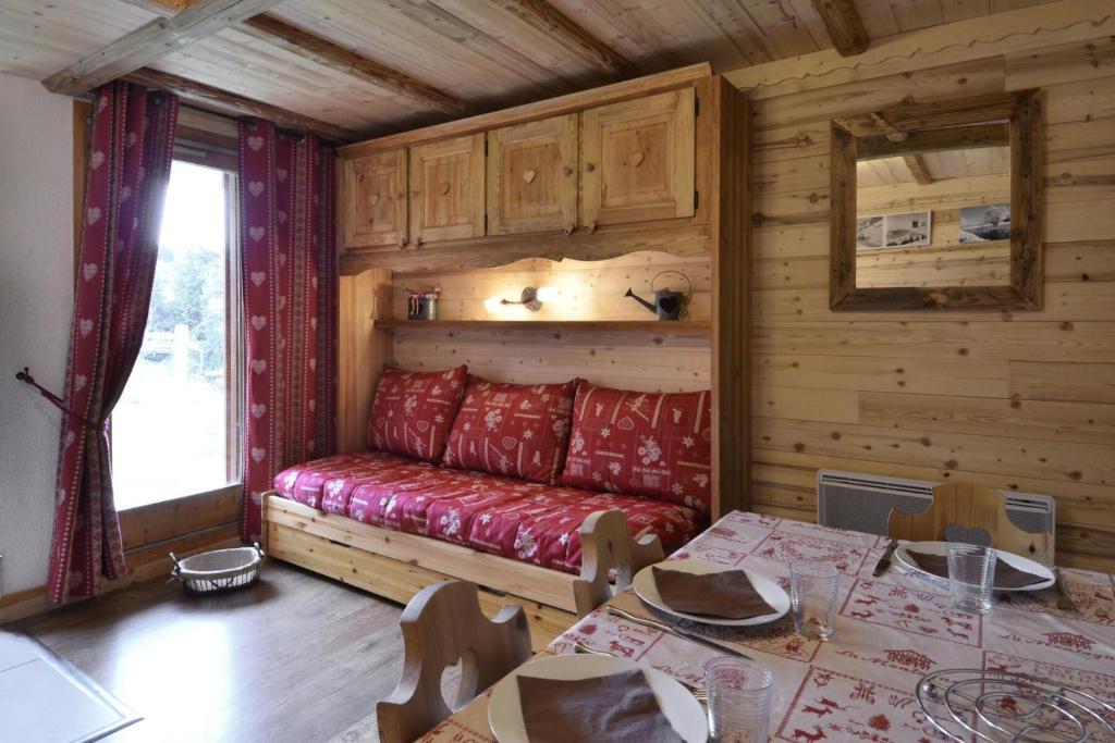 une chambre avec un canapé rouge dans une cabane en rondins dans l'établissement Résidence Onyx - Studio pour 4 Personnes 16, à Mâcot La Plagne