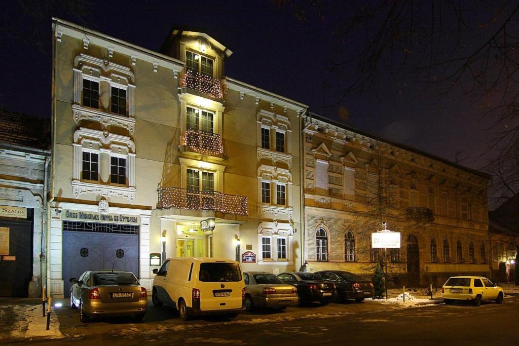 a building with cars parked in front of it at night at Öreg Miskolcz Hotel in Miskolc