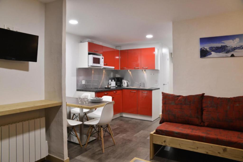 - une cuisine avec des placards rouges, une table et un canapé dans l'établissement Résidence Saint Jacques A - 2 Pièces pour 5 Personnes 15, à Mâcot La Plagne