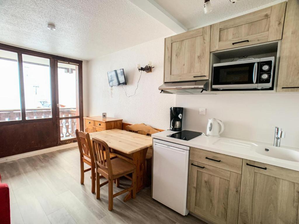 La cuisine est équipée d'une table, d'un évier et d'un four micro-ondes. dans l'établissement Résidence Rond Point Des Pistes B - Studio lumineux·Proche des pistes et des commerces MAE-6792, à Tignes