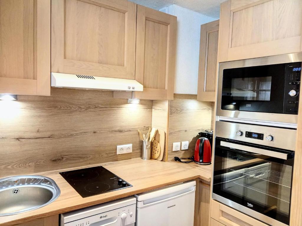 La cuisine est équipée de placards en bois, d'un évier et d'un four micro-ondes. dans l'établissement Résidence Carroley A - 2 Pièces pour 4 Personnes 48, à Mâcot La Plagne